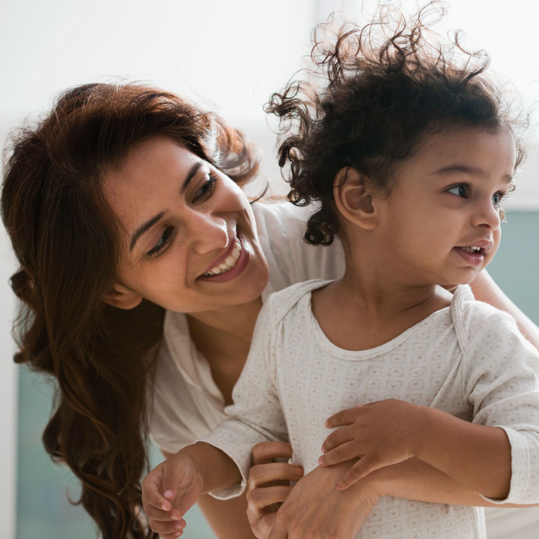 A South Asian mother laughing with her young child